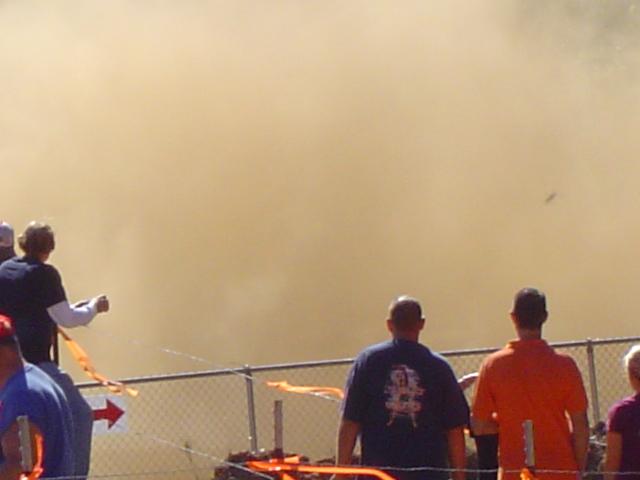 Spectators watch a large dust cloud at an outdoor event