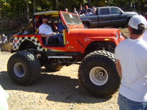 1979 Ford Bronco - A modified Jeep with large off-road tires and a distinctive checkerboard design on its rear panel is seen at an outdoor event.