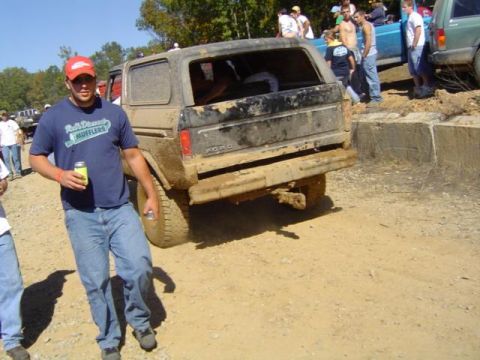 1979 Ford Bronco - A group of people gather around a muddy Ford Bronco at an outdoor event.
