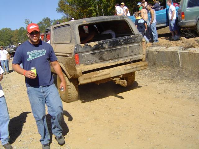 Muddy 1979 Ford Bronco parked on dirt with people around