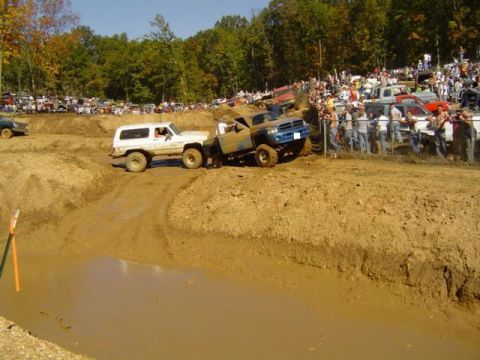 1979 Ford Bronco - Spectators watch as vehicles attempt to traverse a challenging mud pit during an off-road event.