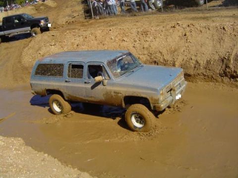 1979 Ford Bronco - A blue SUV navigates a challenging muddy terrain during an off-road event.