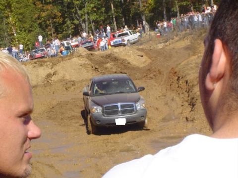 1979 Ford Bronco - A crowd watches as a Dodge Dakota navigates a challenging muddy terrain during an event.