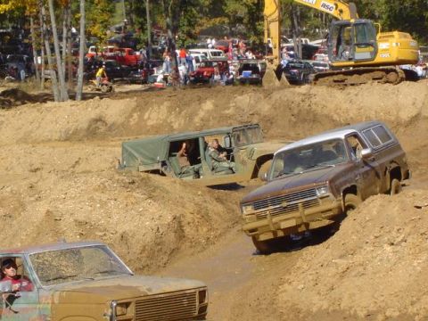 1979 Ford Bronco - Off-road vehicles navigate a muddy course during an event, with an excavator visible in the background.