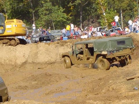 1979 Ford Bronco - A military-style Humvee navigates a challenging mud bog during an off-road event.