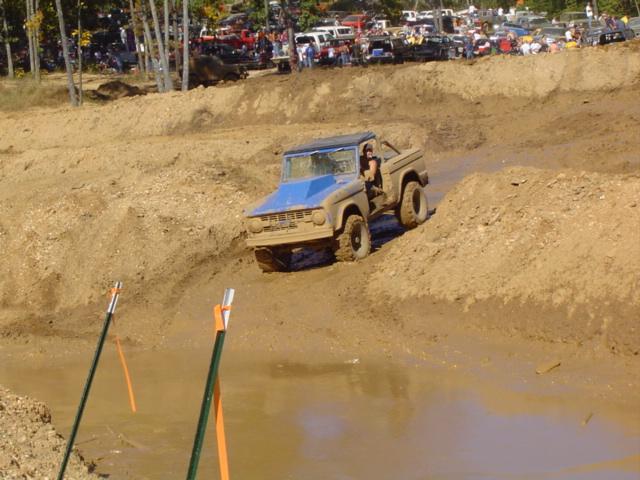 Ford Bronco driving through mud pit with spectators in background