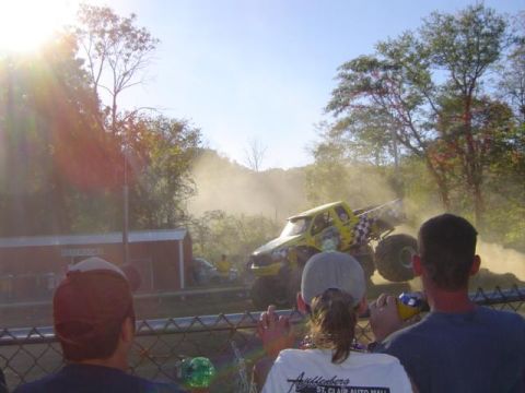 1979 Ford Bronco - A monster truck event is underway with a yellow truck in action, viewed by a crowd.