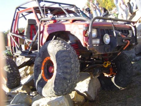 1979 Ford Bronco - This heavily modified off-road vehicle is navigating a rocky terrain with a custom roll cage and oversized tires.