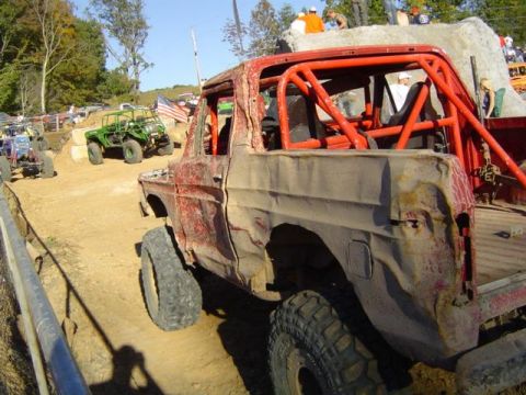 1979 Ford Bronco - Several off-road vehicles participate in a mud event, with a heavily modified red vehicle in the foreground.
