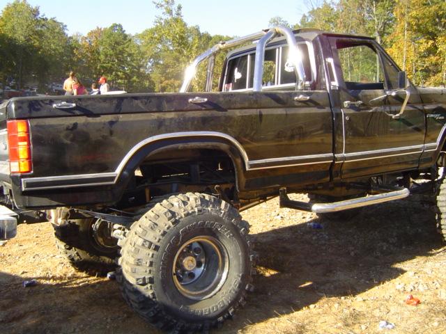 Lifted black pickup truck with chrome roll bar and large off-road tires. Side view shows chrome trim and running boards. Appears to be from the early 1980s