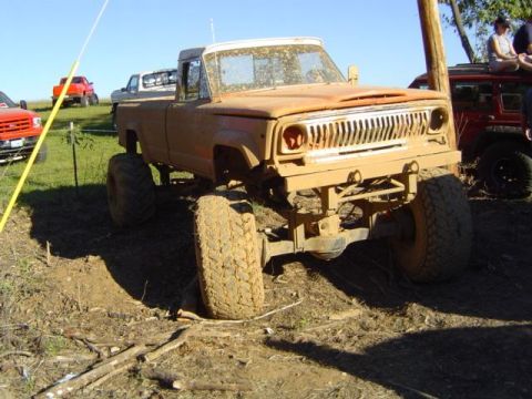 1979 Ford Bronco - A muddy 1979 Jeep J-10 pickup truck is seen at an off-road event with other vehicles.