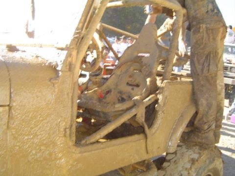 1979 Ford Bronco - A heavily mud-caked off-road vehicle's interior is shown, with a roll cage and racing seat visible.