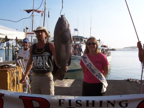 1999 Jeep TJ - A man and a woman pose with a large fish catch at a waterfront event with boats in the background.