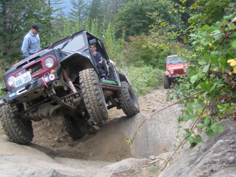 1990 Ford Bronco - Two off-road vehicles tackle a challenging rocky trail, with the lead vehicle demonstrating impressive articulation.