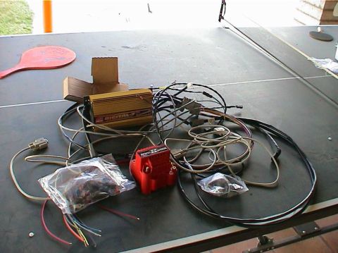 1979 Ford Bronco - A collection of automotive ignition system components, including a digital ignition box and coil, are laid out on a surface.