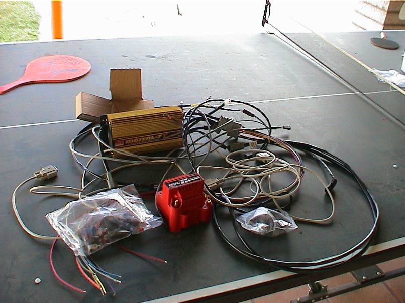Gold digital ignition box and red ignition coil with wiring harnesses on a table