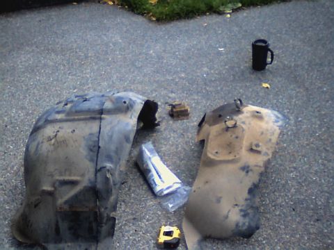 1987 Ford Bronco II - Two used fender liners are laid out on the ground, possibly for replacement or repair.