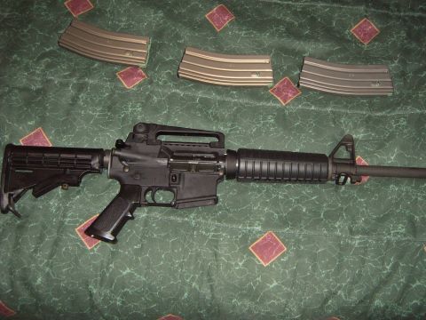1988 Ford Bronco - An assault rifle and three magazines are laid out on a patterned surface, with a website logo in the corner.