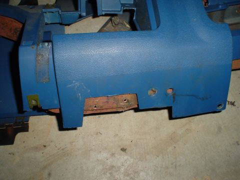 1984 Ford Bronco - A close-up view of a blue plastic automotive dashboard component, showing signs of wear and rust on its mounting brackets.