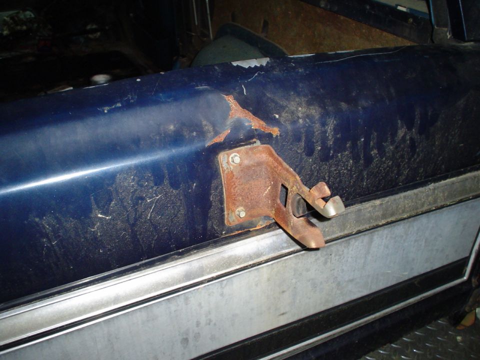 Blue interior door latch mechanism with rust on mounting bracket