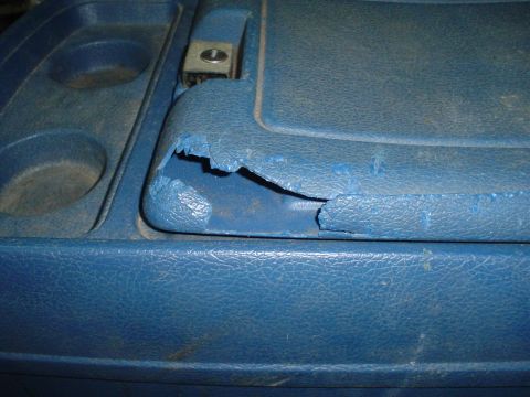 1984 Ford Bronco - The blue interior console shows wear and tear, with a significant rip on the armrest.
