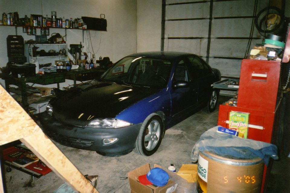 Dark blue and black sedan with a black hood, parked in a garage
