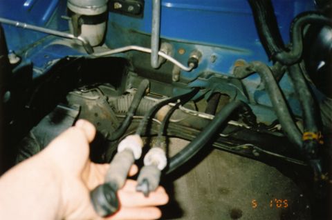 1996 Chevrolet Cavalier - Close-up of a hand holding spark plug wires in an engine bay.