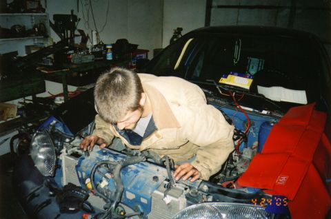 1996 Chevrolet Cavalier - A man is working on the engine of a black 1996 Chevrolet Cavalier in a garage.