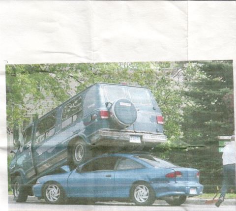 1996 Chevrolet Cavalier - A blue van is precariously balanced on top of a blue coupe, creating an unusual scene.