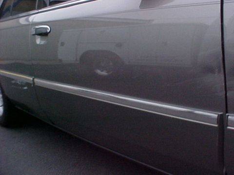 2000 Mercury Grand Marquis - The side of a car shows a reflection of a white work van.