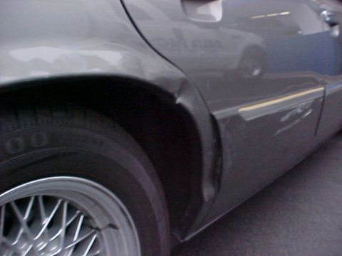 2000 Mercury Grand Marquis - Damage to the rear quarter panel of a 2000 Mercury Grand Marquis, near the wheel.