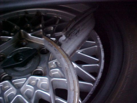 2000 Mercury Grand Marquis - The image shows a damaged alloy wheel and tire, with a bent metal piece obscuring part of the wheel.