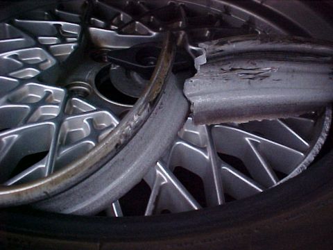 2000 Mercury Grand Marquis - Close-up of a damaged alloy wheel rim, showing a bent and broken section.