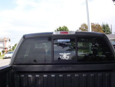 2004 Ford F-150 - Rear view of a pickup truck's tinted window, displaying various stickers and a reflection of the surroundings.