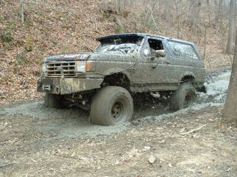 1988 Ford Bronco - Muddy 1988 Ford Bronco navigating a difficult off-road path.