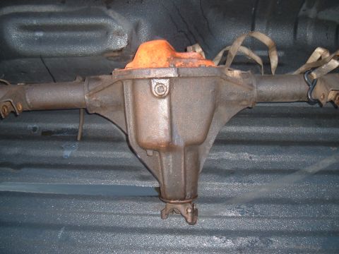 1989 Ford Bronco - Rear differential assembly with an orange cover, secured with straps inside a vehicle's cargo area.