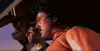 1995 Ford Bronco - A close-up shot captures two men peering out from inside a vehicle, their faces illuminated by the sun.