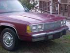 1994 Ford Crown Victoria - The front end of a maroon sedan is shown parked outdoors on a grassy area.