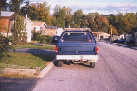 1990 Dodge Charger - Rear view of a blue 1990 Dodge Ramcharger parked on a street with mobile homes in the background.
