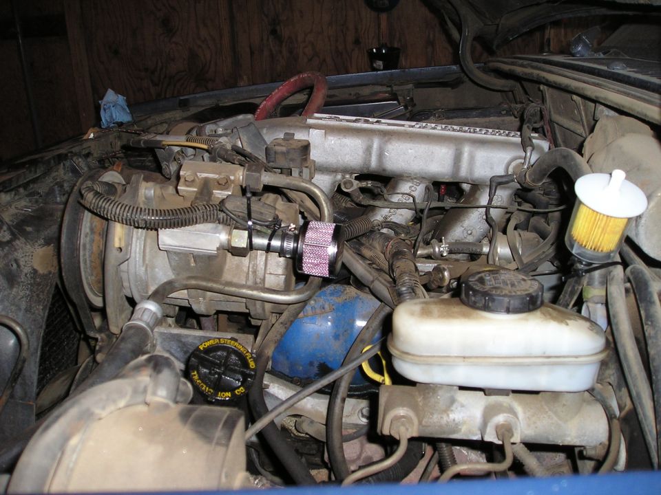 Engine bay showing air compressor, brake fluid reservoir, and aftermarket air filter on intake