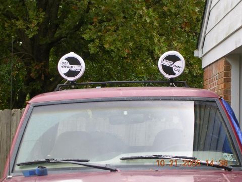 1989 Ford Bronco II - Two auxiliary lights are mounted on the roof rack of a vehicle. The lights have 'EUROCOMP 130' printed on them.