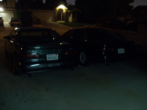 1995 Ford Taurus - Two sedans, one identified as a 1995 Ford Taurus, parked in a driveway at night.