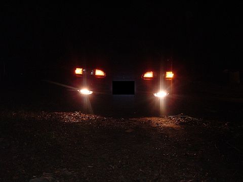 1994 Ford Thunderbird - The front of a 1994 Ford Thunderbird is visible at night, with its lights on.