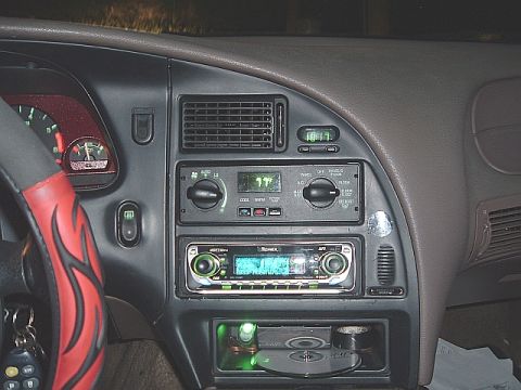 1994 Ford Thunderbird - The interior of a car shows the dashboard with a digital clock, climate controls, and an aftermarket stereo system.