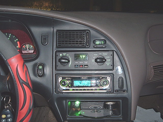 Car dashboard with aftermarket stereo, CD player, and flame-patterned steering wheel cover