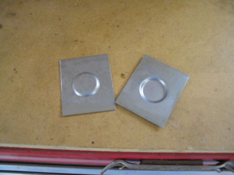 1979 Ford Bronco - Two metal plates with circular indentations are shown on a textured surface.