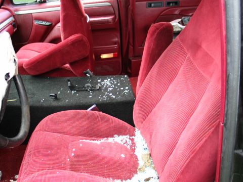 1994 Ford Bronco - The interior of a 1992 Ford Bronco shows red velour seats and debris scattered on the floor and console.