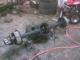 1986 Ford Bronco - Rear axle assembly removed from a vehicle, resting on jack stands in a workshop.