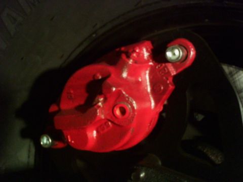 1986 Ford Bronco - Close-up of a red brake caliper mounted near a tire.