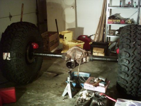 1986 Ford Bronco - Rear axle assembly and tires are staged in a garage, possibly for repair or modification.